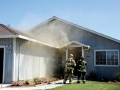Smoke billows out of a Westside Blvd. home Monday afternoon as firefighter prepare to enter and put out the blaze.